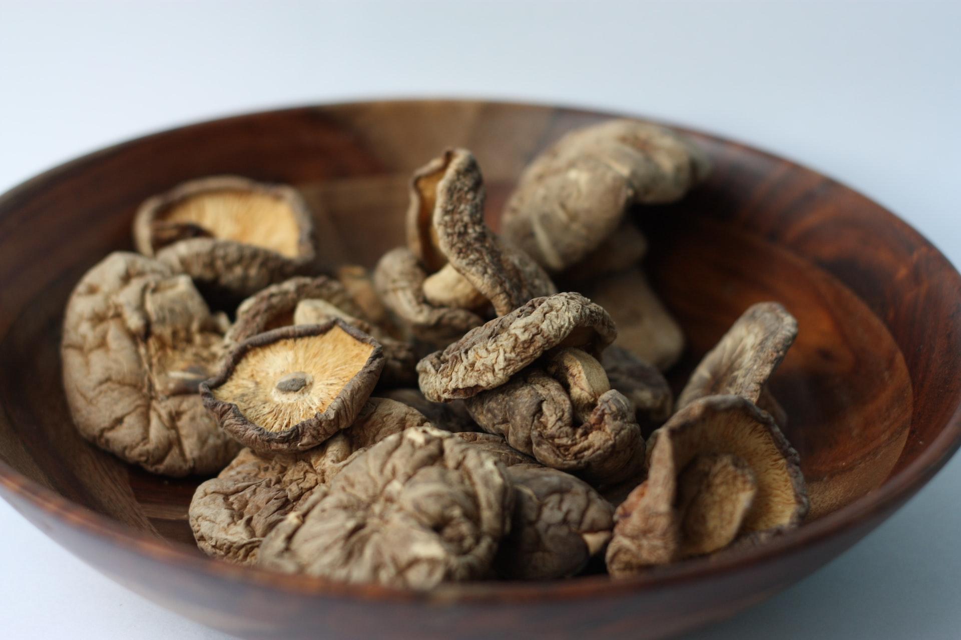 brown and black coffee beans in brown wooden bowl