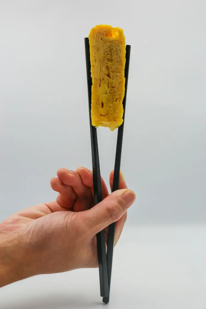 a hand holding two sticks with food on them