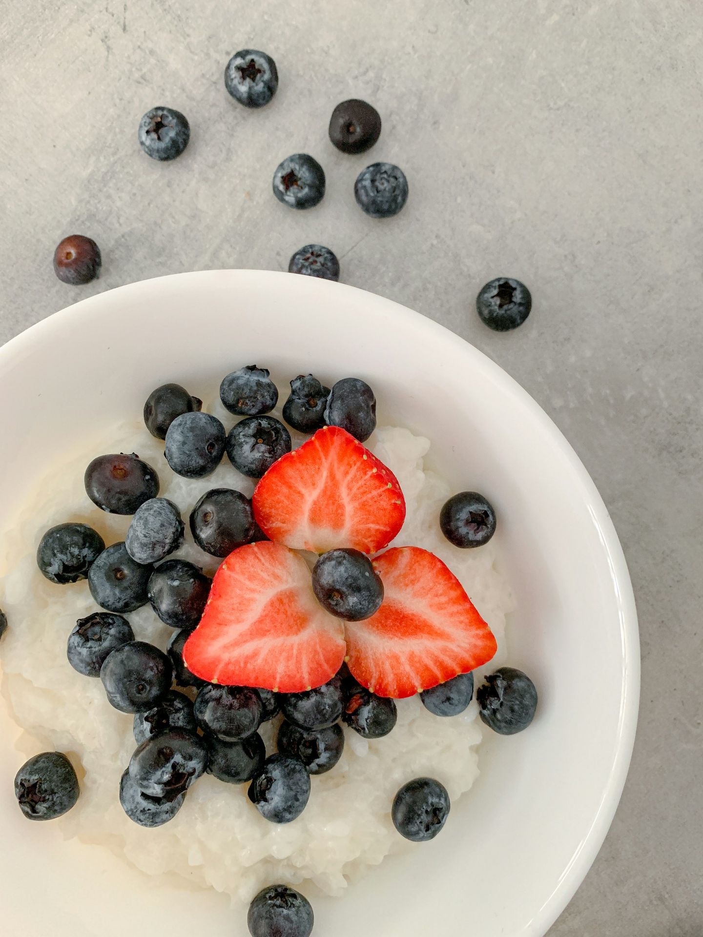 sliced strawberries and blueberries in white ceramic bowl