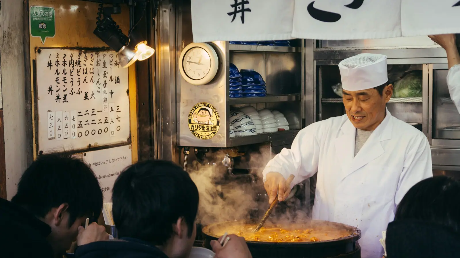 A ramen chef cooking at the counter of a Japanese restaurant