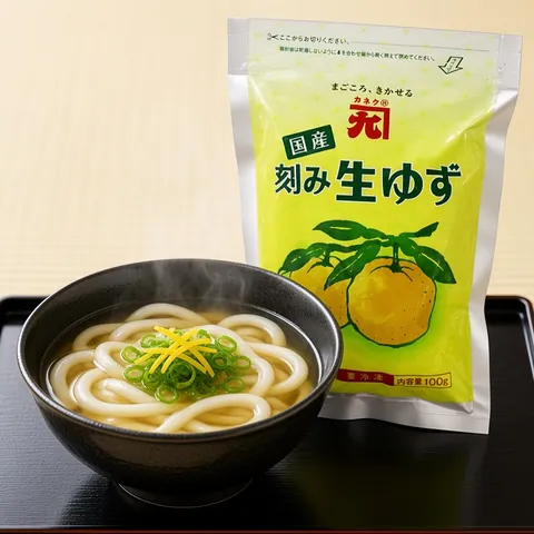 Udon in clear broth with spring onion and yuzu peel in front of a Kaneku yuzu pouch