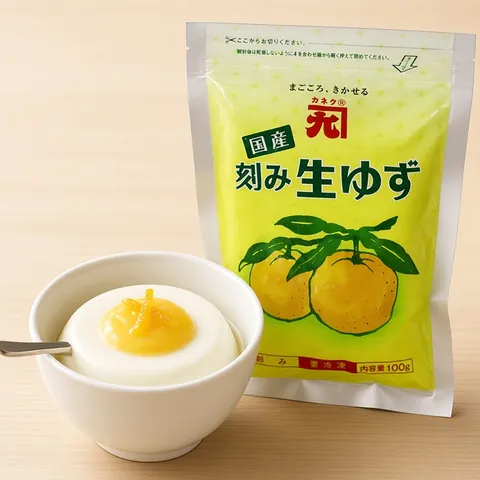 Yuzu panna cotta topped with yuzu curd in a white ceramic cup beside a Kaneku yuzu pouch