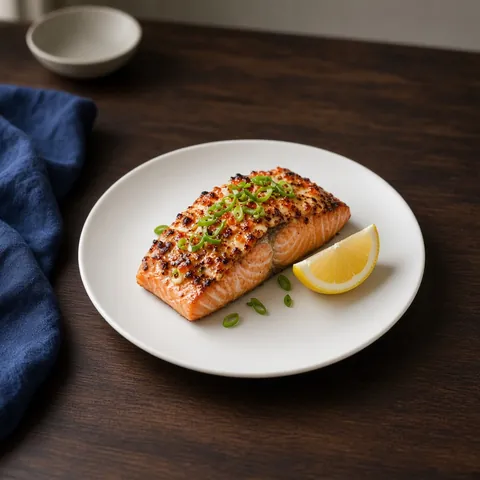 Torched salmon fillet glazed with spicy masago mayonnaise, spring onion and lemon on a white plate