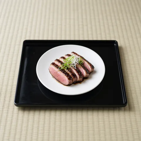 Sliced seared duck breast lacquered with a sweet glaze on a black lacquer tray