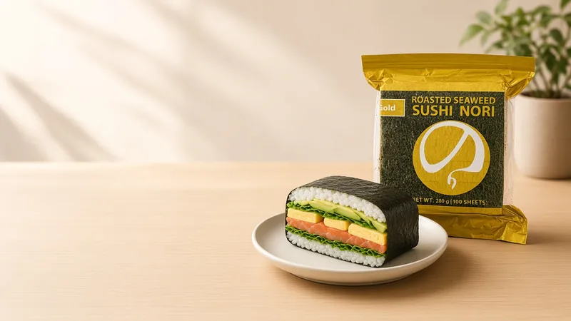 An onigirazu sushi sandwich cut in half to show egg, avocado and salmon layers beside a GGFT Gold sushi nori bag