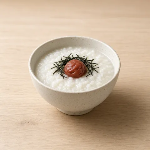 Bowl of white rice porridge topped with one umeboshi